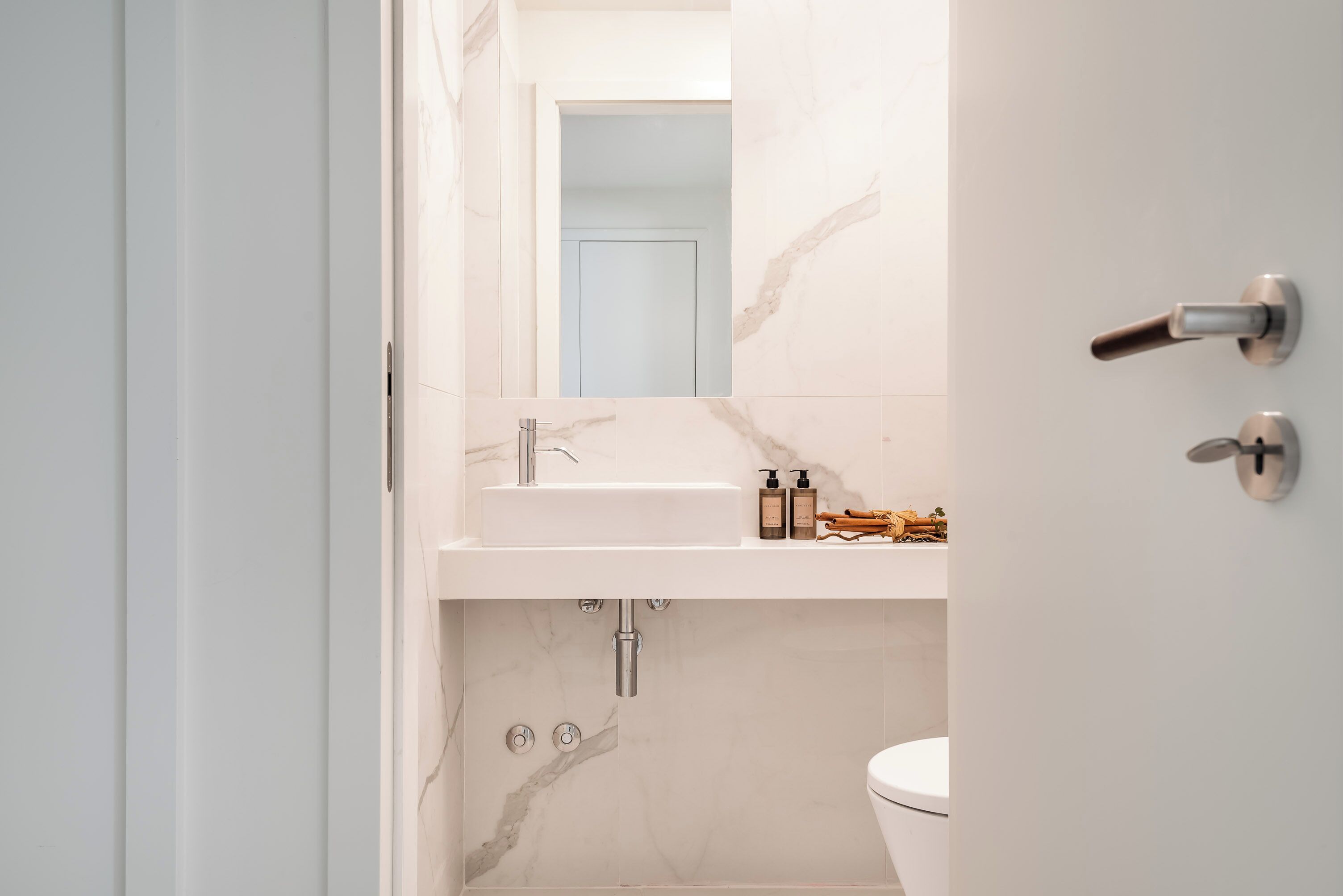 A modern bathroom with a marble sink, a toilet, and a mirror.
