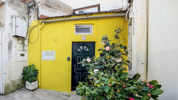 A yellow building with a black door, numbered 5, and a small window above the door. - Real01 · Tiny Little Home in the City Centre (Lisbon)