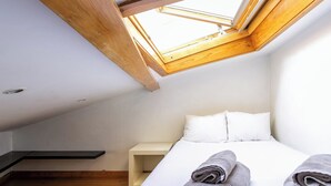 A bedroom with a skylight, a bed with pillows, and a bedside table. - Real01 · Tiny Little Home in the City Centre (Lisbon)