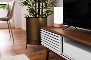 A modern living room with a wooden TV stand, a large flat-screen TV, a potted plant, and a white radiator. - Gaia23 · Lovely 2-bed w/ Parking Amazing View (Vila Nova de Gaia)