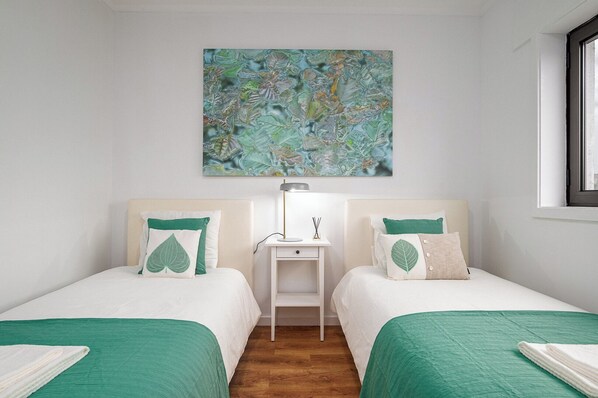 A hotel room with two beds, a nightstand, a lamp, and a large abstract painting on the wall. - Gaia23 · Lovely 2-bed w/ Parking Amazing View (Vila Nova de Gaia)