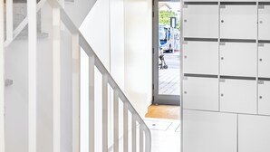 A modern interior with a staircase leading to a door, a white wall, and a tiled floor.