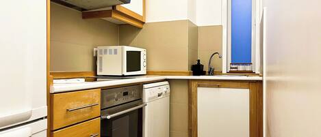 A compact kitchen with a microwave, oven, and dishwasher.