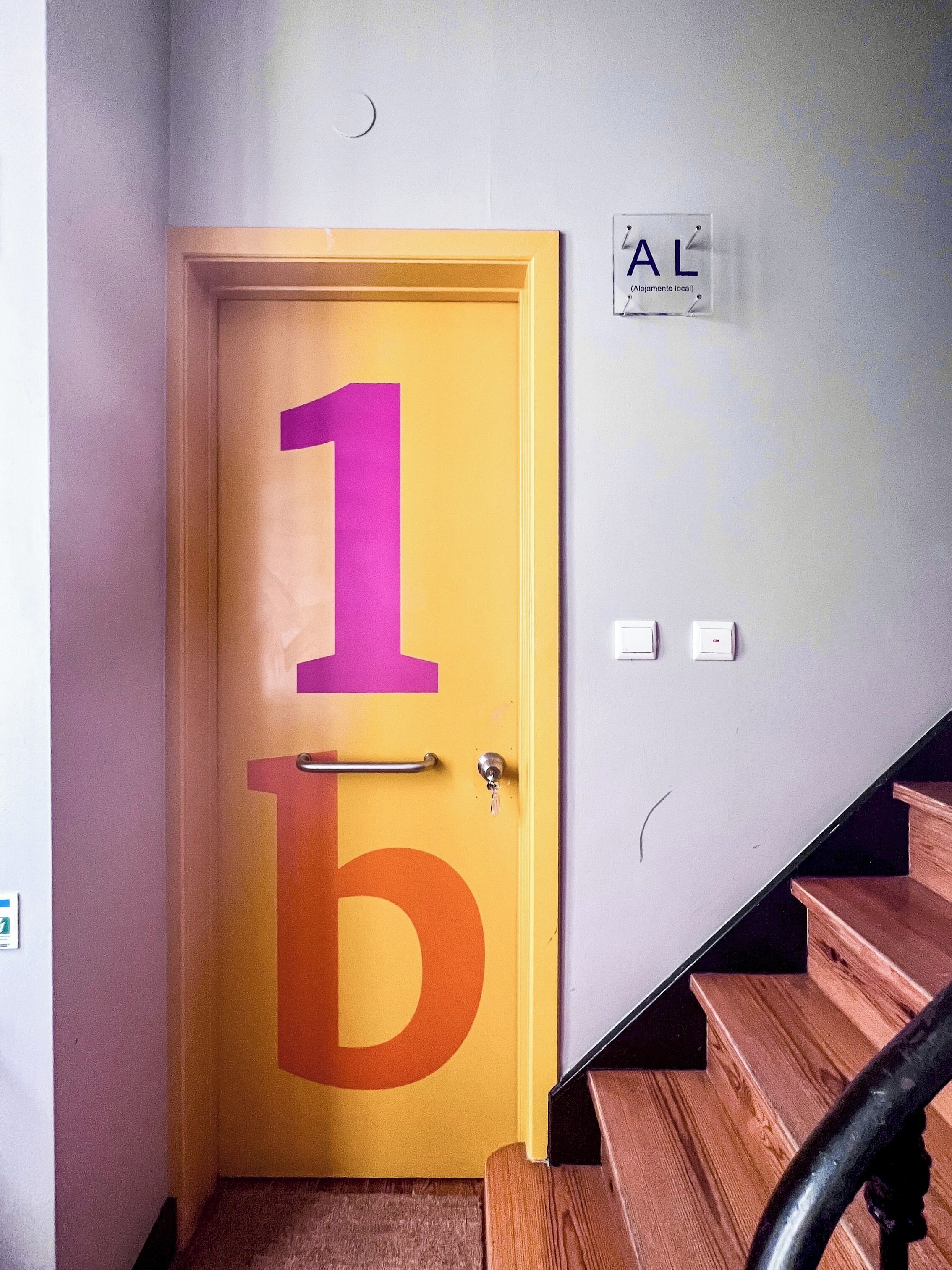Une porte avec une grande plaque portant l’inscription « 1b », une poignée en métal et un trou de serrure.