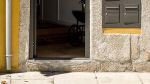 Un acceso que da a un edificio con una pared amarilla y base de piedra. Hay un cartel pequeño con las letras “AL” en la pared.