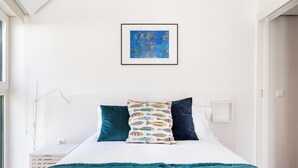 Una camera da letto con un letto, una finestra, un quadro appeso al muro e una porta.