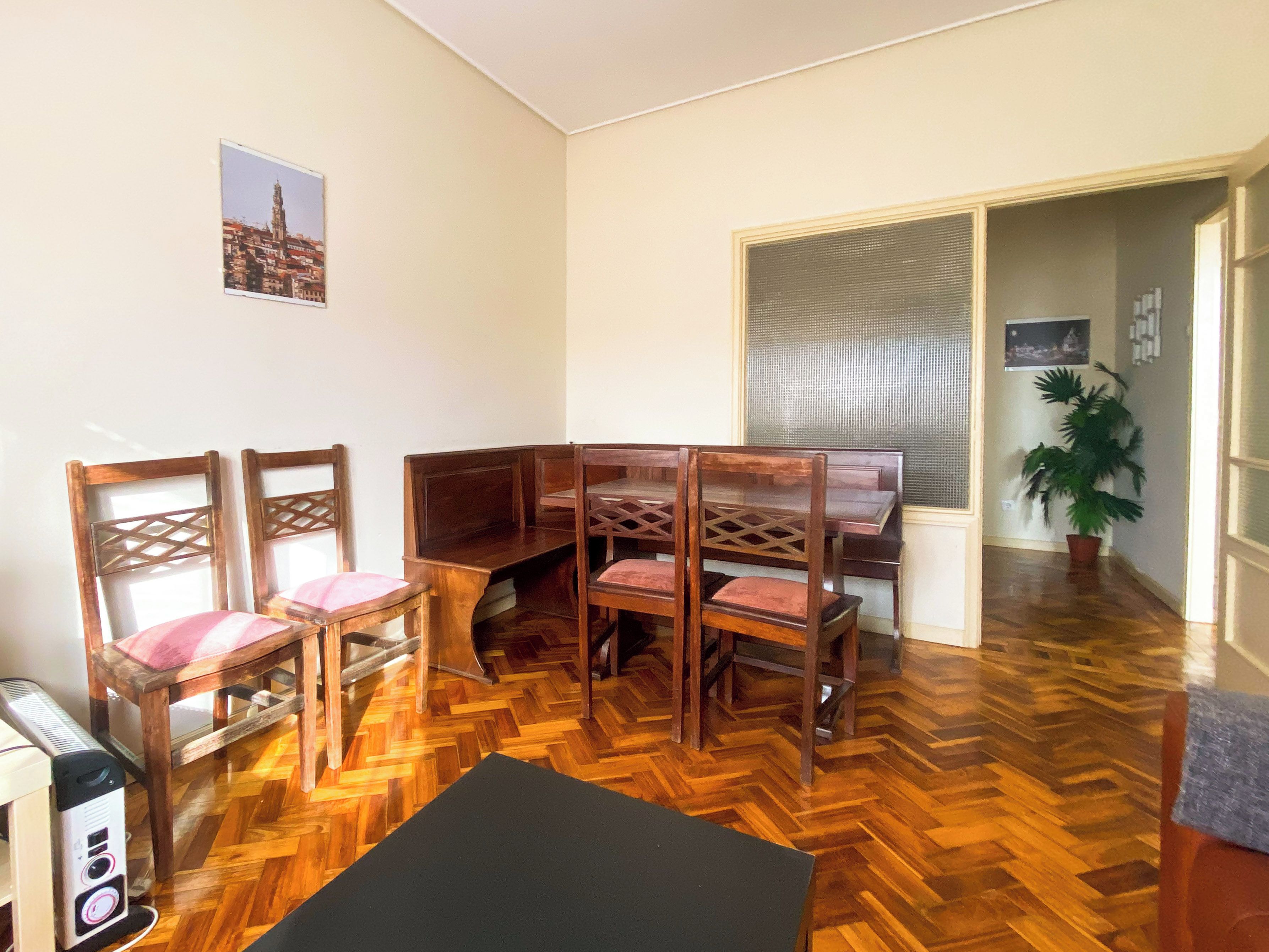 Une pièce dotée d’un parquet en bois à motifs chevrons, d’un pouf noir et d’un canapé d’angle avec une structure en bois et des coussins moelleux.