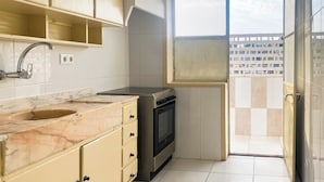 Una cucina compatta con lavello, fornelli e pensili.