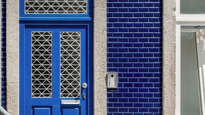 Une porte bleue ornée d’un motif en forme de grille métallique et dotée d’une petite fente pour le courrier.
