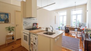 A modern kitchen with a marble backsplash, stainless steel sink, and wooden flooring. - Urbsc3 · Santa Catarina Studios · Apt 3 (Porto)