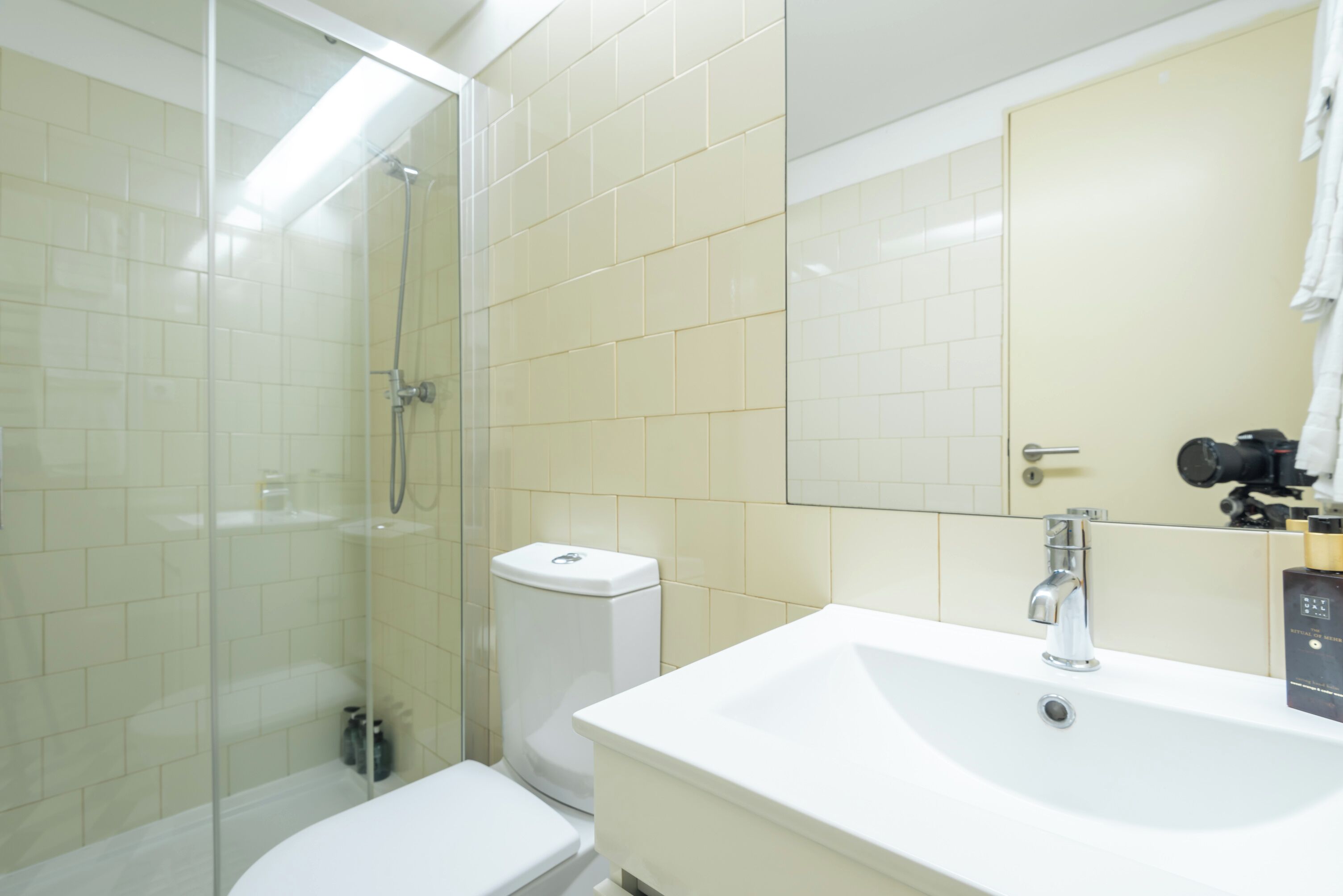 A modern bathroom with a glass shower enclosure, a white toilet, and a sink with a mirror above it.