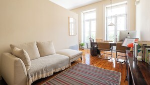 A living room with a sofa, a coffee table, a desk with a computer, and a bookshelf. - Urbsc3 · Santa Catarina Studios · Apt 3 (Porto)