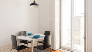 A dining area with a round table, black chairs, and a pendant light.