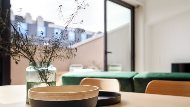 A dining table with a bowl and a vase of dried plants. - Herois · Lovely 2-bed in the City Centre (Porto)