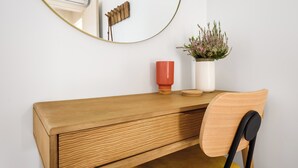 A wooden desk with a mirror, a red vase, and a potted plant. - Herois · Lovely 2-bed in the City Centre (Porto)