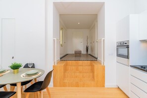 A modern kitchen with a built-in oven and a dining area with a table set for two. - Prt003 · Charming Apartment Porto (Porto)