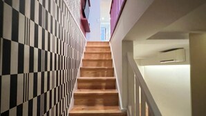 A staircase with black and white checkered walls and wooden steps. - Santos · Designer Retreat: 1 Bedroom apt (Lisbon)