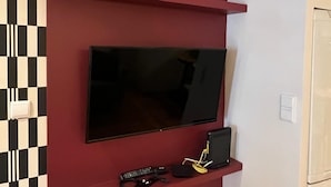 A flat-screen TV mounted on a red wall with a black and white checkered pattern below. - Santos · Designer Retreat: 1 Bedroom apt (Lisbon)