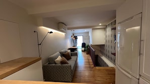 A modern kitchen with a built-in refrigerator, wooden countertops, and a patterned sofa. - Santos · Designer Retreat: 1 Bedroom apt (Lisbon)