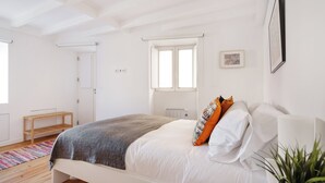 A bedroom with a bed, a bedside table, a window, and a radiator. - Flora2 Flora Apartments, 1 BR on 1st Floor (Porto)
