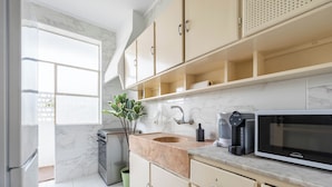 A modern kitchen with marble countertops, a built-in oven, a coffee maker, and a microwave. - Marino · 3bed apt Close to Casa da Musica (Porto)