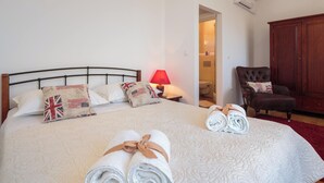 A neatly made bed with pillows, a red lamp, a chair, and a wardrobe in a hotel room. - Impeccable 3-bed House in Supetar (Supetar)