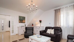 A living room with a glass coffee table, two leather sofas, a white cabinet, and a chandelier. - Impeccable 3-bed House in Supetar (Supetar)