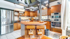 A modern kitchen with wooden cabinets, stainless steel appliances, and a central island with bar stools. - Moss Beach Oceanfront Retreat ~ 20 Mi to San Fran! (Moss Beach)