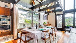 A dining area with a table set for four, wooden chairs, and a view of the outdoors. - Moss Beach Oceanfront Retreat ~ 20 Mi to San Fran! (Moss Beach)