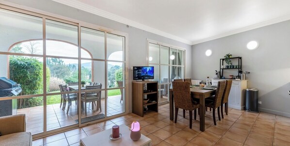 A dining area with a TV, chairs, and a table.
