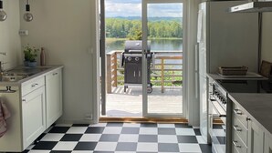 A kitchen with a checkered floor, a view of a lake, and a grill outside. - House at the lake, 3 Bedrooms, WIFI, nature (Västra Götalands län)