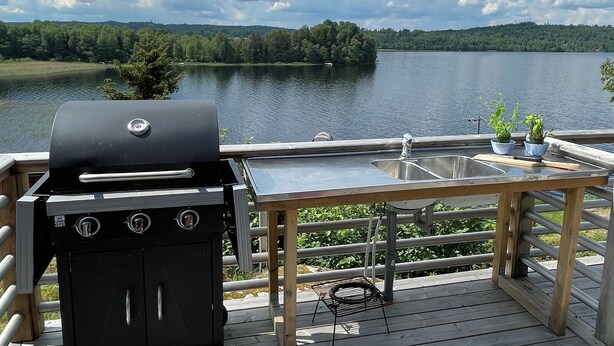 A deck with a grill, a sink, and a view of a lake. - House at the lake, 3 Bedrooms, WIFI, nature (Västra Götalands län)