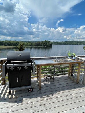Una terrazza con barbecue, lavandino e vista su un lago.