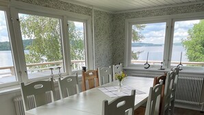 A dining area with a table and chairs, large windows with a view of a lake, and a ceiling with a patterned design. - House at the lake, 3 Bedrooms, WIFI, nature (Västra Götalands län)