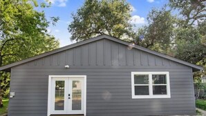 A small, single-story building with a gray exterior and a white door. - Modern Backyard Casita (Bryan)