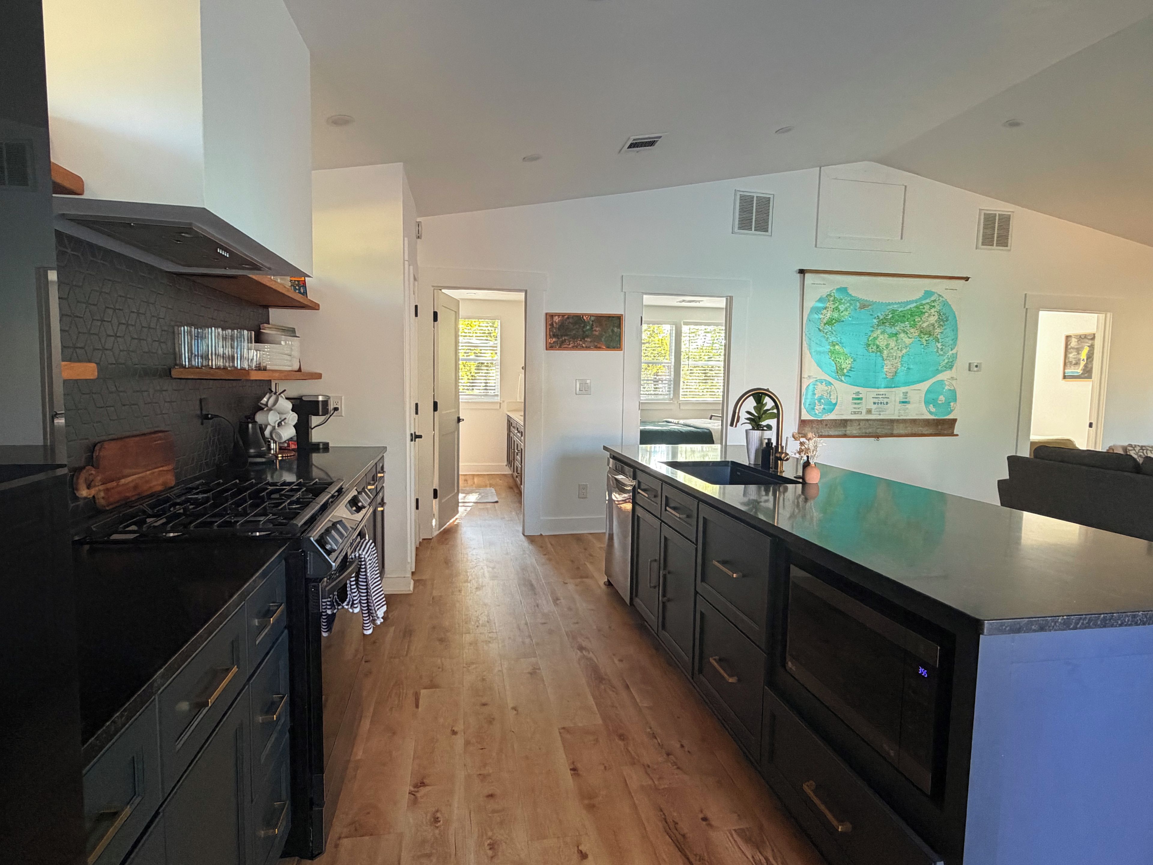 A modern kitchen with a central island, wooden flooring, and a large wall map.