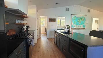 A modern kitchen with a central island, wooden flooring, and a large wall map.