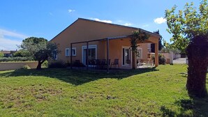 Une maison à deux étages avec un patio couvert et une pelouse.