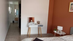 Une chambre à coucher moderne avec un lit, une table de chevet et un petit bureau doté d’un miroir.