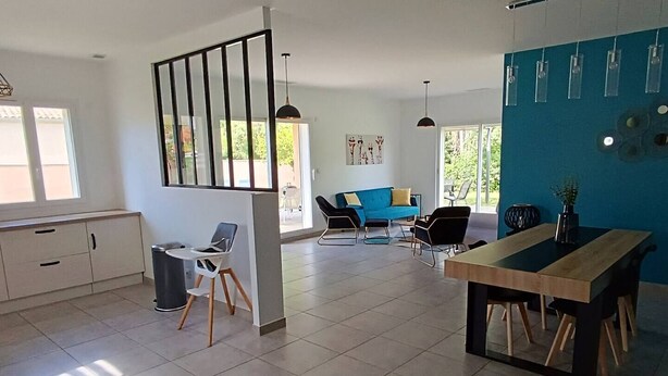Un salon moderne avec un coin repas, un canapé bleu et une table à manger.