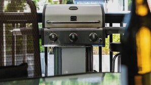A barbecue grill with controls, a bottle of wine, and a view of trees and a house in the background. - Hidden Forest Retreat | King | Firepit | Near Light Rail | Minutes to Downtown Seattle (Seattle)