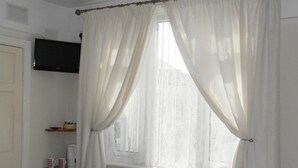 Baño con ventana, radiador y repisa con artículos de aseo.