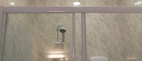 Een badkamer met een douchecabine van glas, een handdouche en een bedieningspaneel aan de muur.