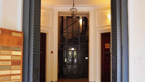 Une entrée imposante, avec un portail en métal noir, une plaque en bois et un escalier menant à un niveau supérieur.