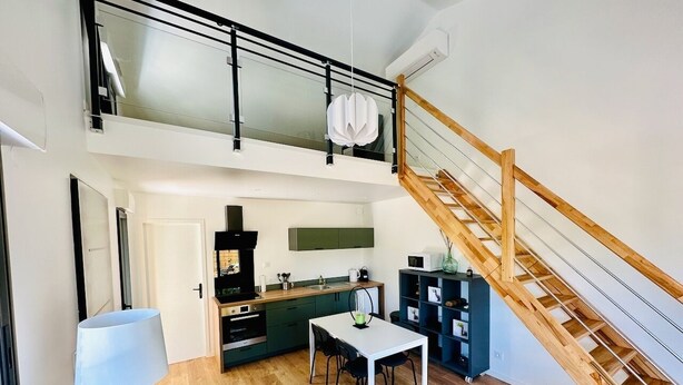 A modern apartment with a kitchen, dining area, and a staircase leading to an upper level. - Le Petit *** - 1 room, all new & all inclusive (Montauban)