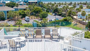 A coastal view with a balcony overlooking a beach, a parking area, and several buildings.