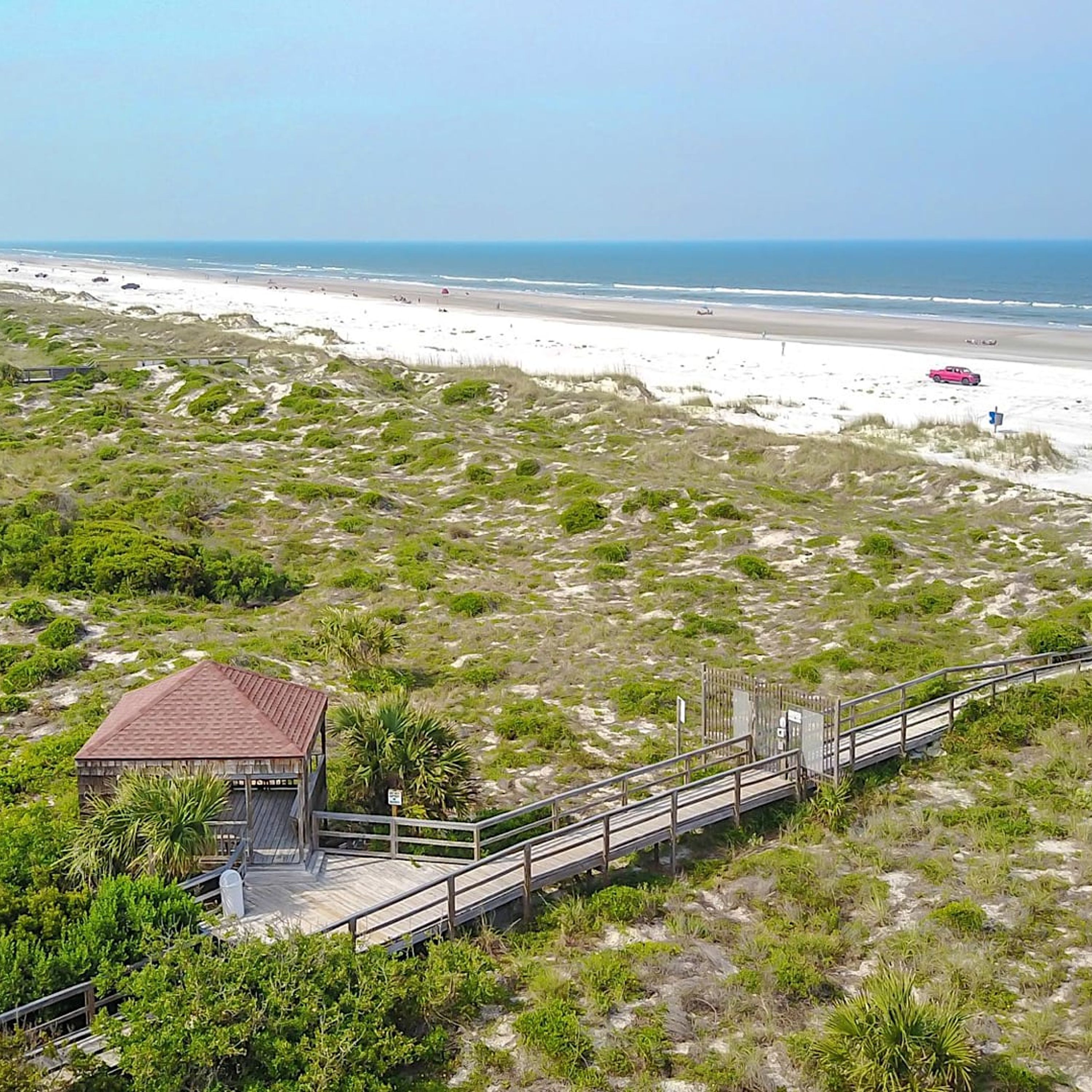 A coastal area with a wooden structure connected to a boardwalk leading to a beach.