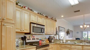 A kitchen with wooden cabinets, a microwave, stove, and various appliances. - Ocean Bliss 2BD Villa on St Augustine Beach (St. Augustine)