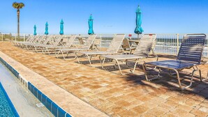 A poolside area with sun loungers and umbrellas, a clear sky, and a palm tree. - Ocean Oasis Relax Near Historic St Augustine (St. Augustine)