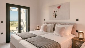 A bedroom with a large bed, two bedside tables, a wall-mounted air conditioner, and a view through a sliding glass door. - The Ionian Sea and Sunset View Villa (Minia)